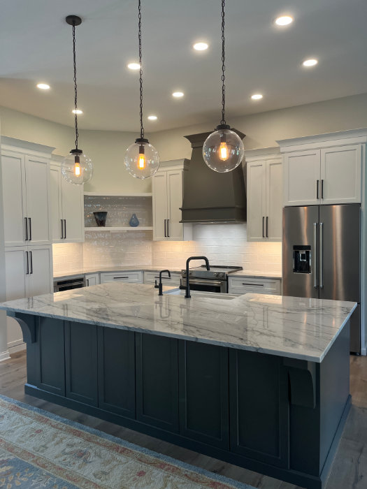 Wide view of the finished kitchen showing the island, range hood and cabinetry